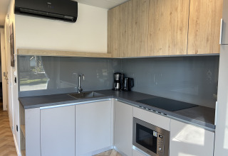Moderne keuken in de Domus 4+2 lodge op Zilverstrand in België, met houtaccenten en apparatuur.