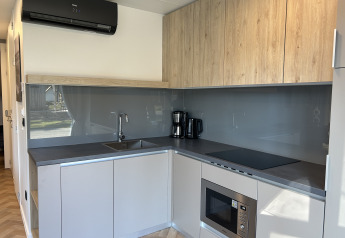 Moderne keukenopstelling in Domus 4+2 op Zilverstrand in België met houten kasten en apparatuur.