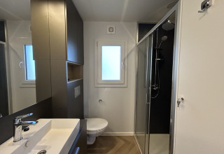Moderne badkamer in Domus 4+2 op Zilverstrand in België met douche, toilet en wastafel.