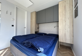Soveværelse med blå seng, træskabe og moderne indretning i Domus 4+2 lodge på Zilverstrand, Belgien.