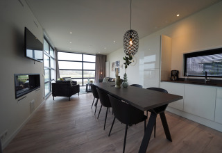 Moderne glampingaccommodatie met open keuken, eethoek, zithoek, grote ramen en stijlvolle inrichting.