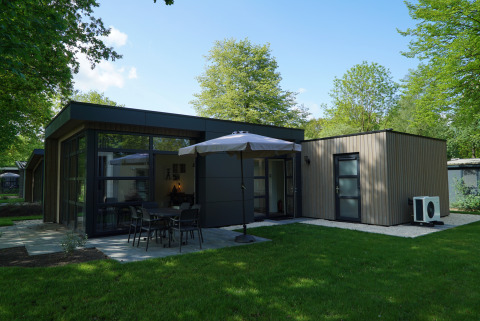 Moderne lodge L-Cube Sauna 4 bij De Utrechtse Heuvelrug, Nederland, met tuin, terras en grote parasol.