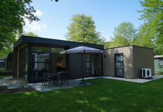 Moderne lodge L-Cube Sauna 4 bij De Utrechtse Heuvelrug, Nederland, met tuin, terras en grote parasol.
