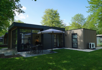 Lodge moderne L-Cube Sauna 4 Ă De Utrechtse Heuvelrug, Pays-Bas, avec terrasse, jardin et parasol.