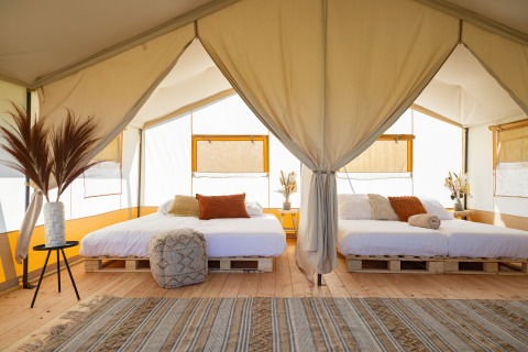 Tenda safari luminosa con due letti matrimoniali su bancali in legno a TinyParks Cast Away, Paesi Bassi.
