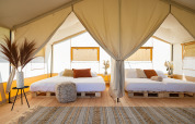 Tenda safari luminosa con due letti matrimoniali su bancali in legno a TinyParks Cast Away, Paesi Bassi.