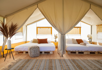 Tenda safari luminosa con due letti matrimoniali su bancali in legno a TinyParks Cast Away, Paesi Bassi.