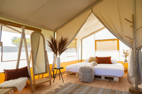 Interior de la tienda Safari Tent Lodge en TinyParks Cast Away, Países Bajos, con cama grande y decoración acogedora.