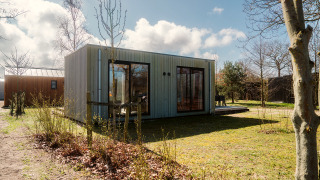 Eine moderne Lodge namens Duunroos im Holiday Park De Klepperstee in den Niederlanden, umgeben von Natur.