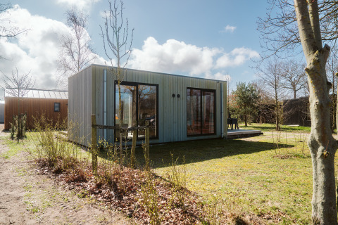 Moderne lodge Duunroos op vakantiepark De Klepperstee in Nederland, omgeven door natuur en bomen.