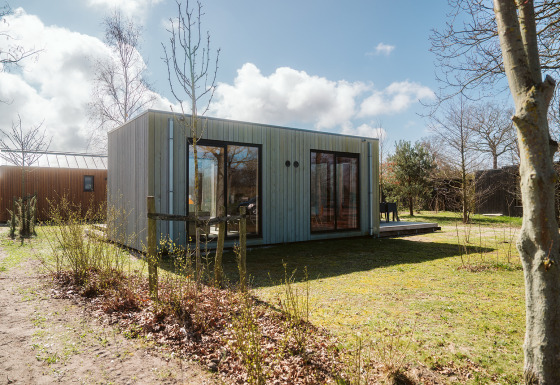 Moderne lodge Duunroos op vakantiepark De Klepperstee in Nederland, omgeven door natuur en bomen.