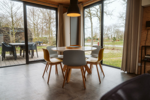 Moderne eethoek in lodge Duunroos bij Holiday park De Klepperstee, Nederland, met uitzicht door grote ramen.