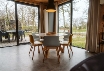 Comedor moderno en la cabaña Duunroos, Holiday park De Klepperstee, Países Bajos, con ventanales al exterior.
