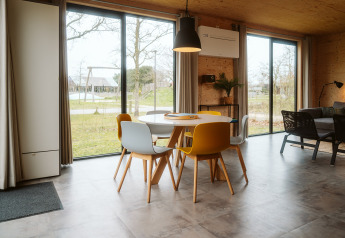 Moderne eethoek met gekleurde stoelen en grote ramen in de Duunroos-lodge, De Klepperstee, Nederland.