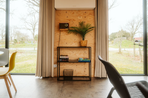 Interior moderno de lodge en Duunroos, Holiday park De Klepperstee, con ventanales, estantería y vista rural.