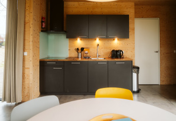 Cocina moderna en la cabaña Duunroos del parque vacacional De Klepperstee, Países Bajos, con paredes de madera.