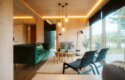 Moderne woonkamer in Ark Shelter bij vakantiepark De Klepperstee, Nederland, met groene zetel en grote ramen.