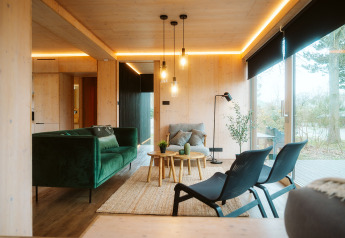 Moderne woonkamer in Ark Shelter bij De Klepperstee, Nederland, met groene bank en grote ramen.