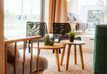 Lyst, moderne opholdsområde på Ark Shelter, De Klepperstee, med sofaer, træborde og planter.