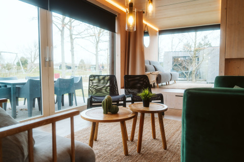 Sala de estar en Ark Shelter, casa natural en el parque vacacional De Klepperstee, con decoración moderna y ventanales.