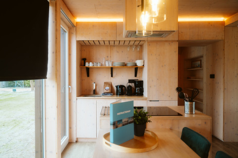 Moderne køkkeninteriør i lyst træ med spisebord, vindue og hyggelig belysning i Ark Shelter, Holland.