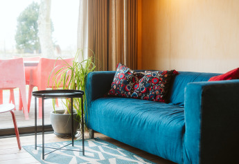 Sala de estar en The Hoagte, tiny house en Holiday park De Klepperstee, con sofá azul y cojín decorativo.