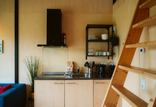 Cocina moderna con interior de madera y escalera en una tiny house en el parque De Klepperstee, Países Bajos.