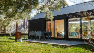 Buitenterras van t Kroaje lodge in vakantiepark De Klepperstee, Nederland, met zitjes en groen uitzicht.