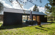 Cabaña moderna de madera oscura con terraza en el parque vacacional De Klepperstee, Países Bajos.