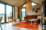 Sala luminosa en una tiny house del Holiday park De Klepperstee, Países Bajos, con muebles modernos.