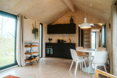 Bright, modern tiny house interior at Punt in Holiday Park De Klepperstee, Netherlands, featuring kitchen and dining area.