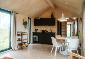 Licht, modern interieur van een tiny house in Punt op Vakantiepark De Klepperstee, Nederland, met keuken en eethoek.