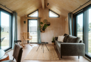 Lichte, moderne woonkamer van tiny house Melle op vakantiepark De Klepperstee in Nederland met grote ramen.