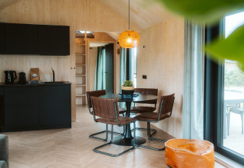 Modern tiny house interieur in Melle op vakantiepark De Klepperstee, Nederland, met eethoek en keuken.