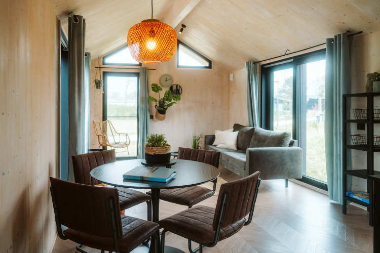 Modernes, helles Wohnzimmer im Tiny House Melle im Ferienpark De Klepperstee, Niederlande, mit Essbereich.