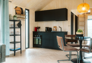 Cocina negra moderna y comedor en la tiny house Melle en Holiday park De Klepperstee, Países Bajos.