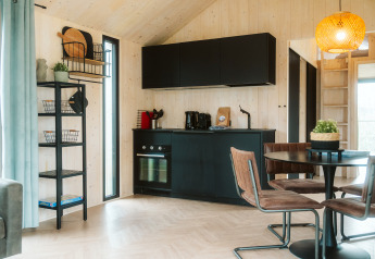 Angolo cottura nero moderno e zona pranzo nella tiny house Melle al Holiday park De Klepperstee, Paesi Bassi.