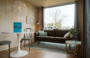 Modern eingerichtetes Wohnzimmer im Tiny Rebel im Holiday Park De Klepperstee mit großen Fenstern und Sofa.