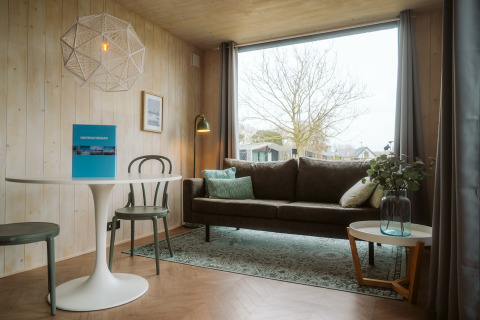 Moderne woonkamer in Tiny Rebel bij Holiday park De Klepperstee met groot raam en comfortabele zithoek.