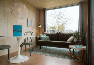 Moderne stue i Tiny Rebel-huset på Holiday park De Klepperstee med store vinduer og stilfuld indretning.
