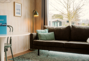 Modernes Wohnzimmer im Tiny Rebel, Holiday Park De Klepperstee, mit grüner Couch und großem Fenster.