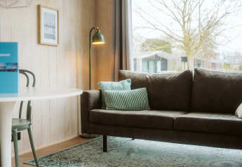 Moderne stue i Tiny Rebel, Holiday park De Klepperstee, med grøn sofa, læselampe og stort vindue.