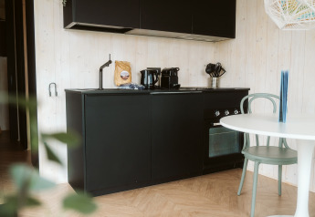 Moderne zwarte kitchenette met apparatuur in tiny house Tiny Rebel op Vakantiepark De Klepperstee, Nederland.