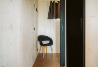 Rincón minimalista en Tiny Rebel, Holiday park De Klepperstee, con silla negra y paredes de madera clara.
