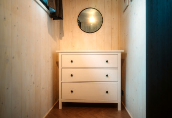 Petit couloir avec commode blanche et miroir rond dans Tiny Rebel, Holiday park De Klepperstee, Pays-Bas.