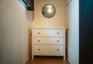 Kleine gang met witte commode en ronde spiegel in Tiny Rebel, Holiday park De Klepperstee, Nederland.
