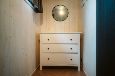 Petit couloir avec commode blanche et miroir rond dans Tiny Rebel, Holiday park De Klepperstee, Pays-Bas.