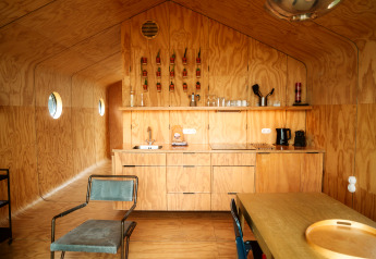 Interiør af et Wikkel tiny house i De Klepperstee, Holland, med krydsfiner vægge og minimalistisk køkken.