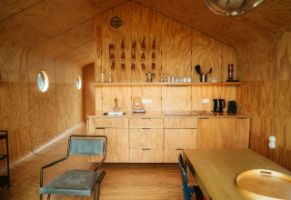 Interior of a Wikkel tiny house at De Klepperstee, Netherlands, featuring plywood walls and a compact kitchen.