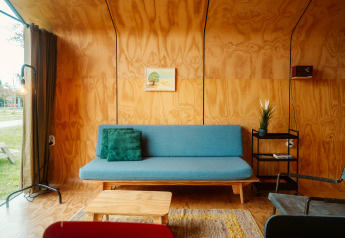 Salon moderne dans la tiny house Wikkel avec canapé bleu et murs en bois à De Klepperstee, Pays-Bas.